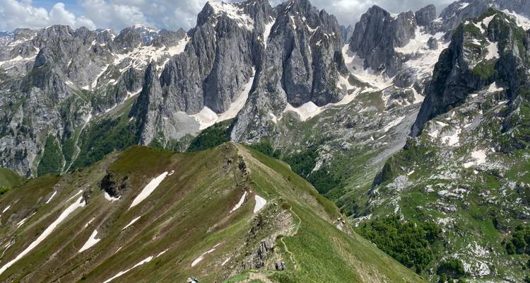 Chaîne de montagnes avec de la verdure et des sommets enneigés.