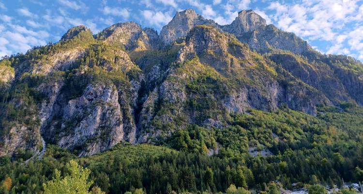 Montagne avec des falaises escarpées et des arbres à la base.