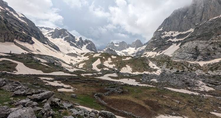 Col de montagne enneigé avec ciel nuageux.