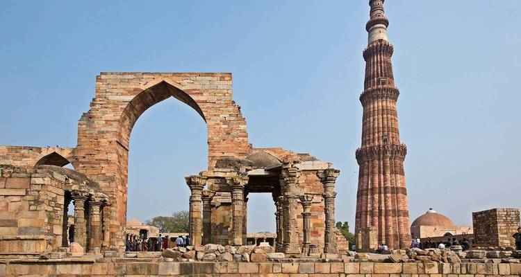 Qutub Minar met omliggende ruïnes op een zonnige dag.
