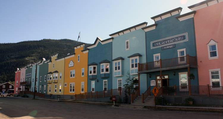 Rangée colorée de bâtiments sur une rue avec des montagnes.