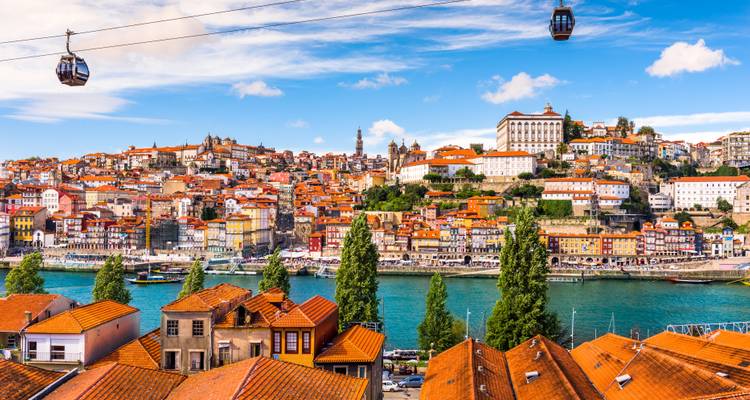 Vista brillante del paisaje urbano de Oporto y teleféricos deslizándose sobre el río Douro en un día soleado.