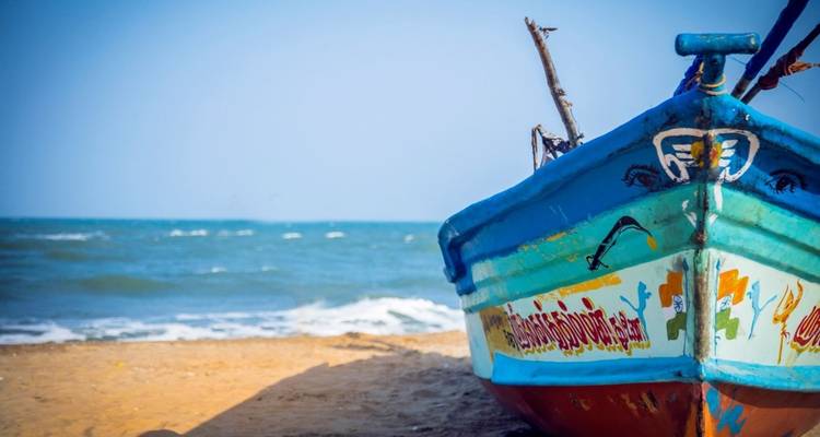 Ein buntes Fischerboot auf einem Sandstrand.
