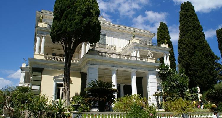 Neoclassical mansion with high trees.