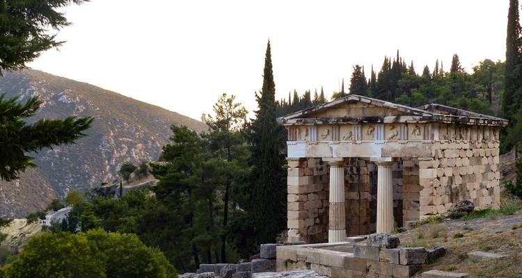 Ancient Greek temple structure with mountain backdrop.