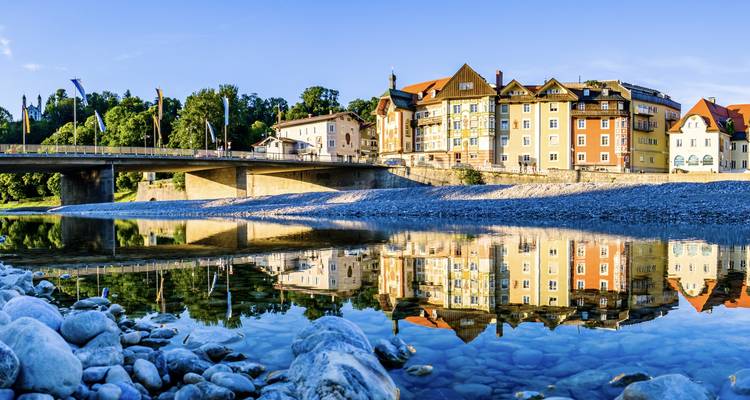 Picturesque town by a river with mountains in the distance.