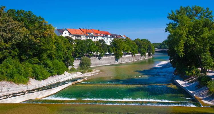 Riverside view with a historic building and lush greenery.