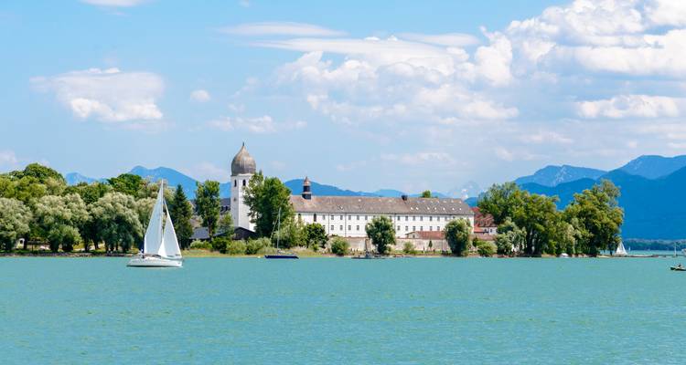 Monastère avec dôme et voiliers sur un lac sous un ciel clair.