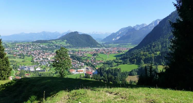 Vue panoramique d'une vallée avec des villages et des montagnes.