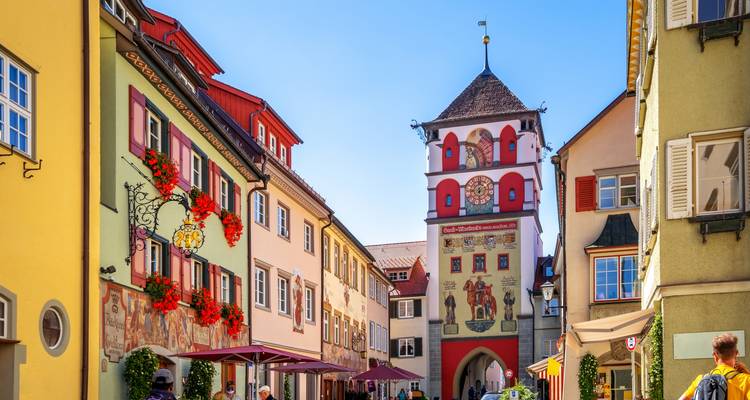 Colorful buildings in a town square with a clock tower in the background.