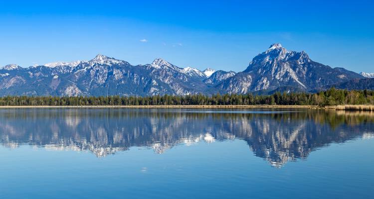 Mountain lake with snowy peaks reflecting on calm water.