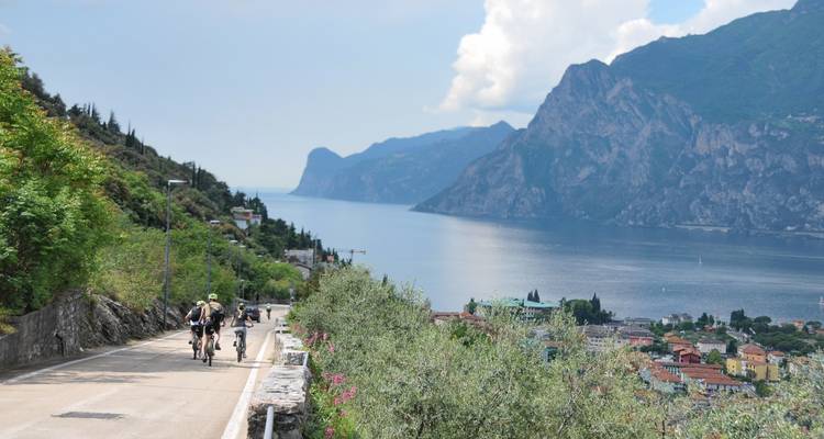 Fietsers rijden over een weggetje langs het meer met een prachtig uitzicht over diepblauw water en torenhoge rotsen