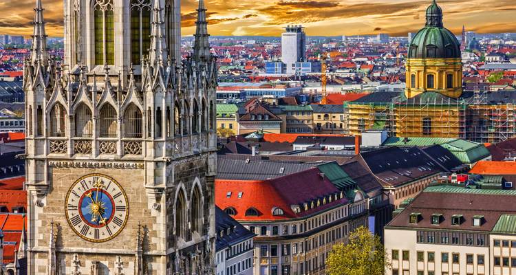 Dramatischer Sonnenuntergang über München mit dem prunkvollen Neues Rathaus Uhrenturm, der sich über die farbenfrohe Stadtlandschaft erhebt.