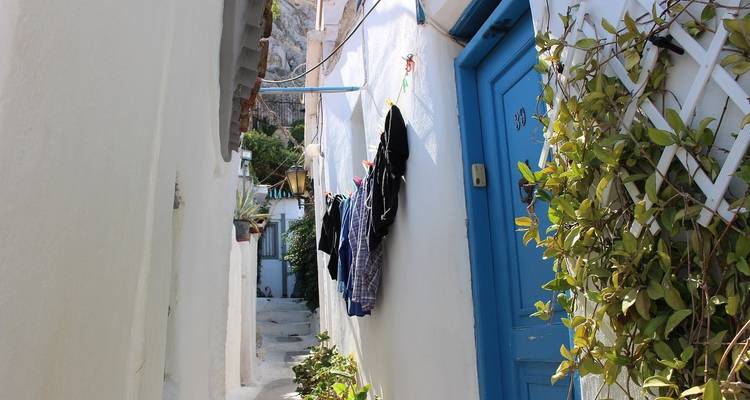 Un callejón estrecho con ropa colgada y una puerta azul.