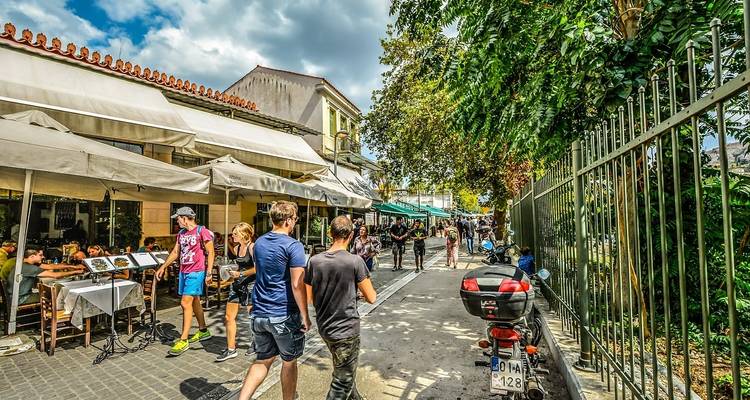Gente caminando por una calle vibrante con cafés y tiendas.