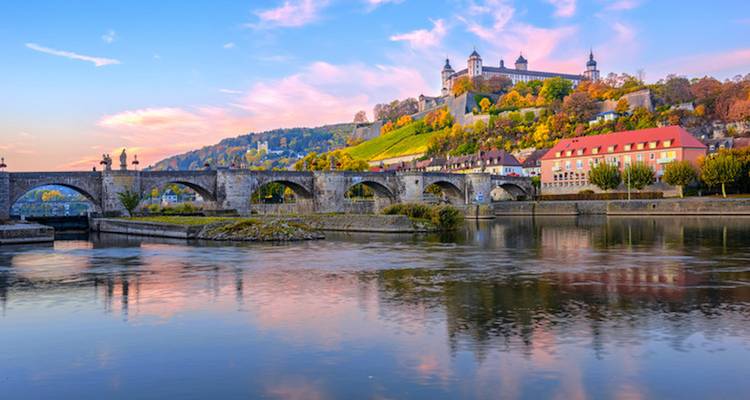 Historic bridge and fortress on a hillside at sunset.
