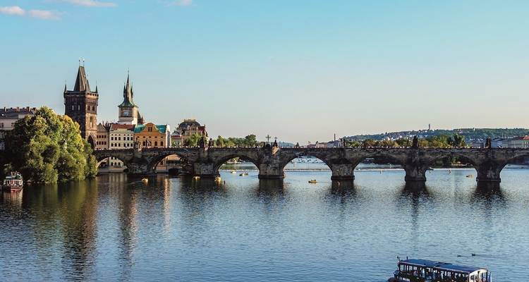 The Charles Bridge in Prague over a river with historic buildings in the background.