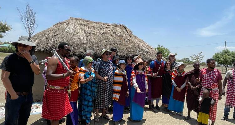 Toeristen in traditionele Maasai-kleding buiten een hut.