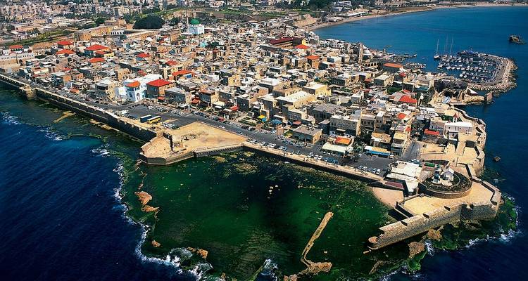 Vue aérienne d'une ville côtière historique avec des fortifications.