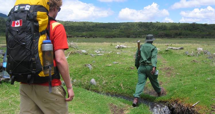 Two people walking in a field, one with a colorful backpack.