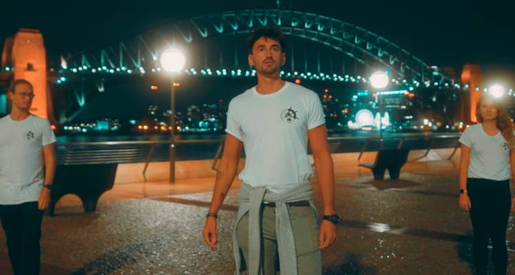 Des gens devant le pont du port de Sydney la nuit.