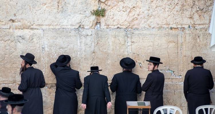 Religieuze locatie met mensen die bidden voor een grote stenen muur.