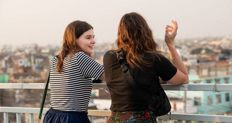 Dos mujeres teniendo una conversación con vista de la ciudad de fondo.