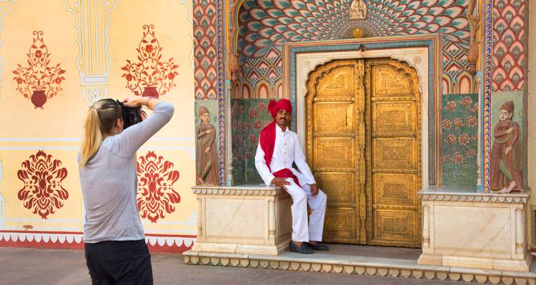 Turista fotografiando a un guardia vestido tradicionalmente junto a la ornamentada Puerta Dorada del Pavo Real en el Palacio de la Ciudad de Jaipur.