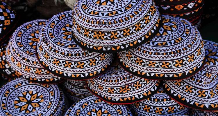 Una pila de gorras bordadas tradicionales coloridas, mostrando artesanía detallada.