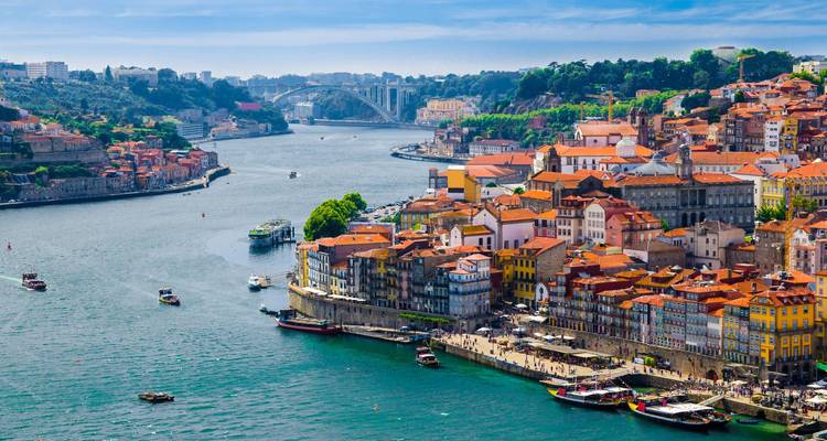 Vista panorámica de los coloridos edificios de la ribera de Oporto y el río Duero con puentes a lo lejos.