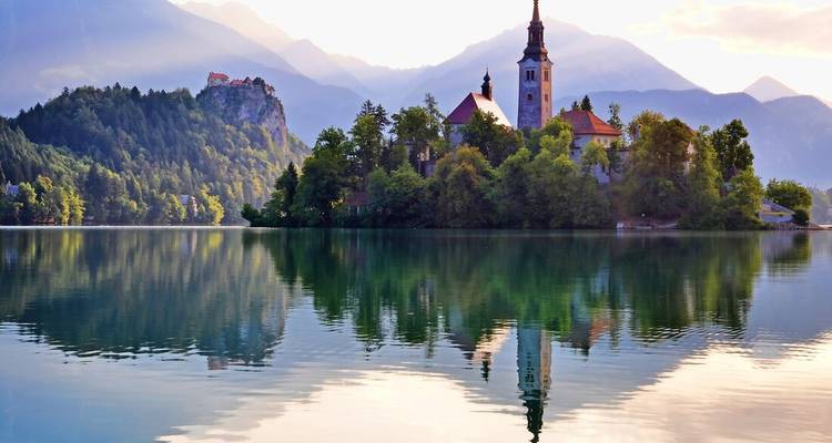 Iglesia icónica en una isla del Lago Bled reflejada perfectamente en aguas tranquilas con un fondo alpino