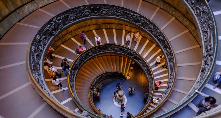 Vista desde arriba de la ornada escalera de doble espiral dentro de los Museos del Vaticano llena de visitantes