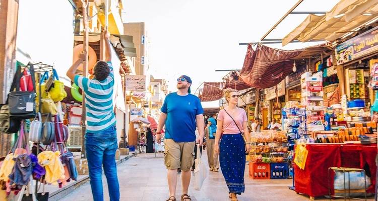 Des touristes explorant un marché animé avec des produits locaux.