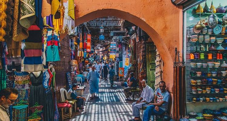 Escena vibrante de mercado con gente bajo un arco en Marruecos.
