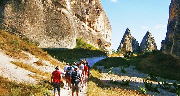 Gruppe von Touristen, die zwischen großen Felsformationen wandern.