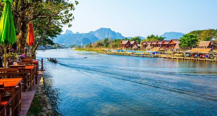 Flussuferszene mit bunten Holzhäusern und Booten.