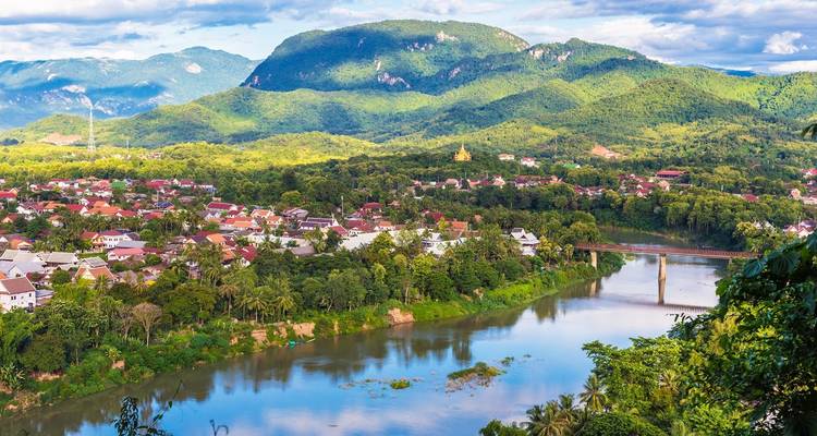 Malerischer Überblick über eine Stadt entlang eines Flusses mit umliegenden Hügeln.