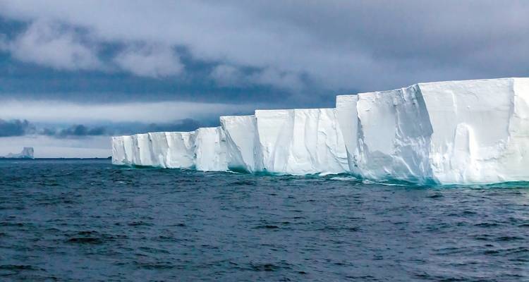 A flat-topped iceberg with a dramatic cloudy sky above.
