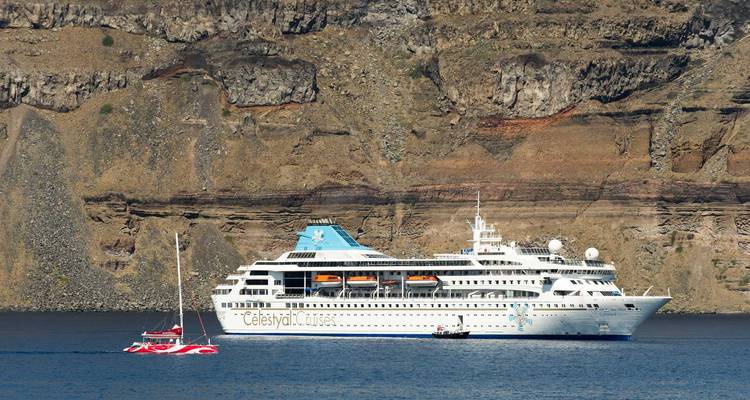 Grand navire de croisière ancré près d'une côte rocheuse.