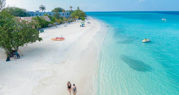 Vue aérienne d'une plage de sable blanc bordée de gens.