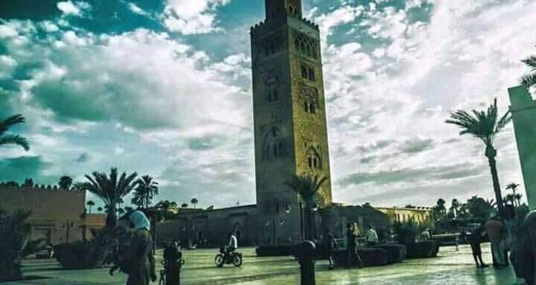 Koutoubia-moskee met palmbomen en mensen op het plein.