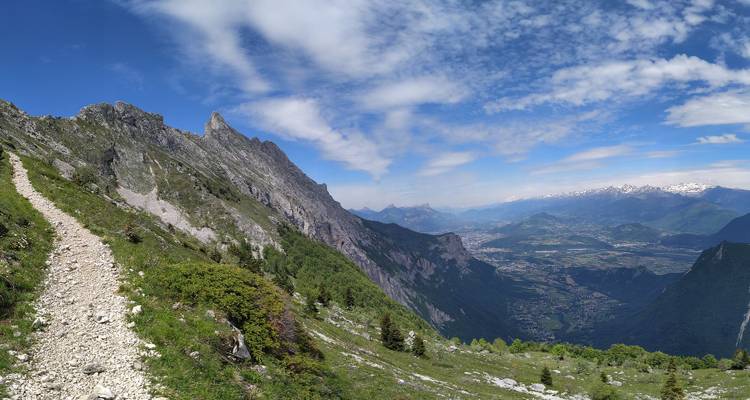 Vue étendue d'une vallée avec un sentier sinueux le long des montagnes.