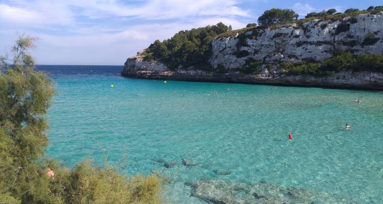 Une magnifique baie turquoise avec une eau cristalline et une falaise rocheuse.