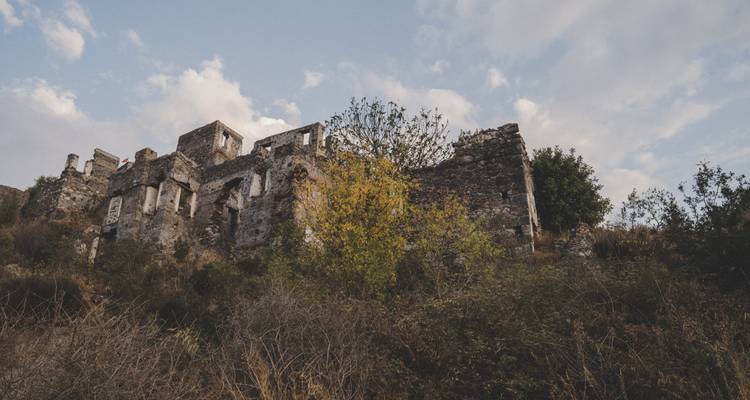 Ruines d'un ancien bâtiment en pierre entouré de végétation.