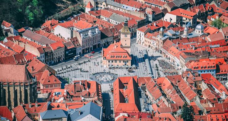 Vue aérienne d'une place de ville avec des bâtiments aux toits rouges.