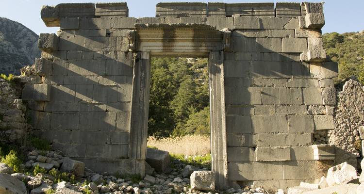 Ancient stone ruins with an open doorway and trees in the background.