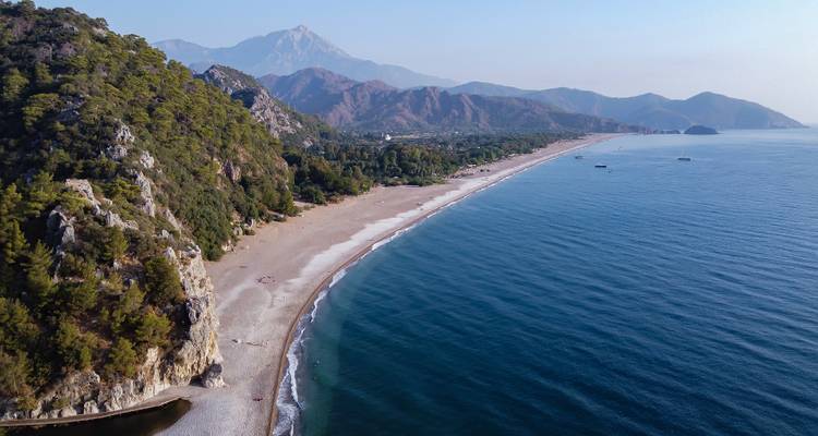 Aerial view of a coastline with a sandy beach and mountains.