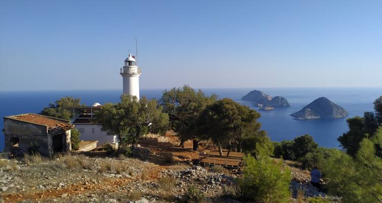 Lighthouse near the sea with islands and trees in the background.
