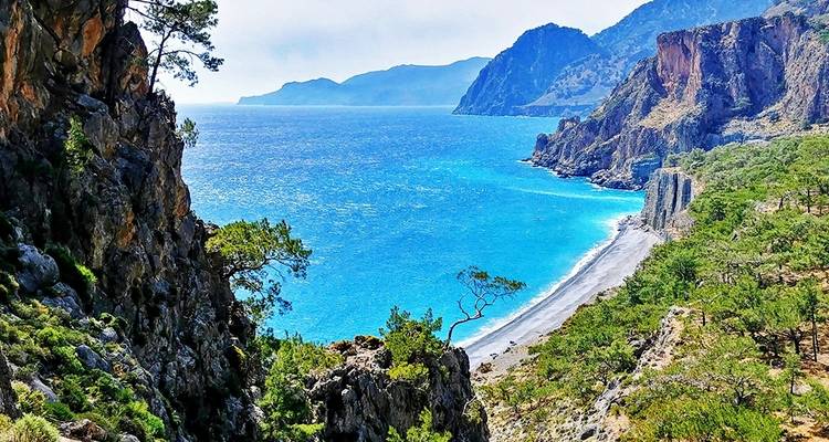 Paysage côtier pittoresque avec une eau d'un bleu éclatant et des falaises rocheuses.