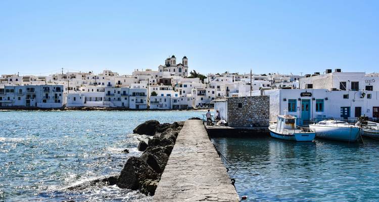 Un muelle de piedra estrecho que conduce hacia un pueblo junto al mar.